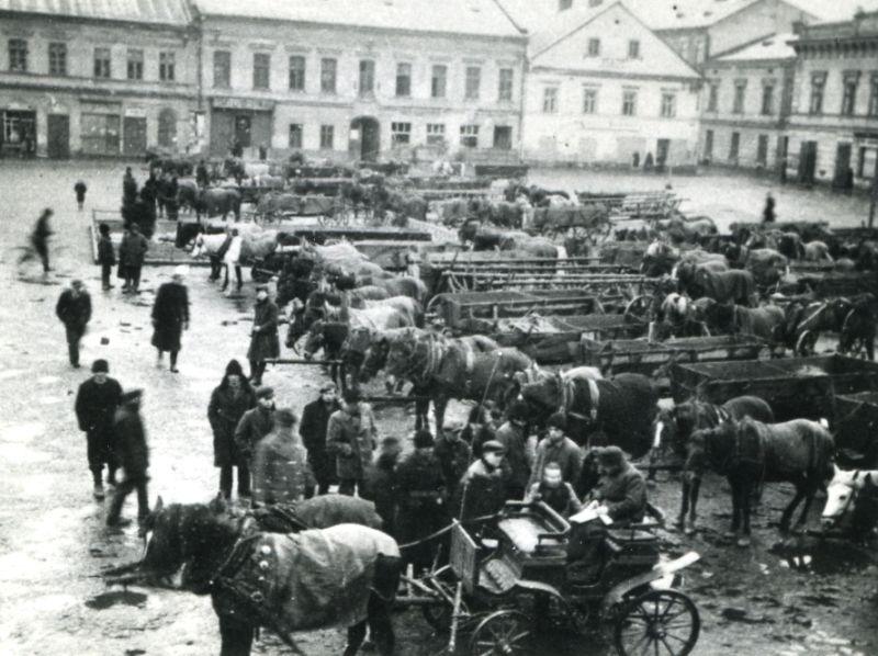 Market Square in Oświęcim. On the market square there are horse-drawn ladder carts arranged in several rows. People are standing by the carts.