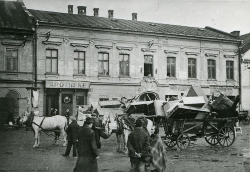 Displacements from Oświęcim. Horse-drawn ladder carts loaded with furniture. People walking around the carts.