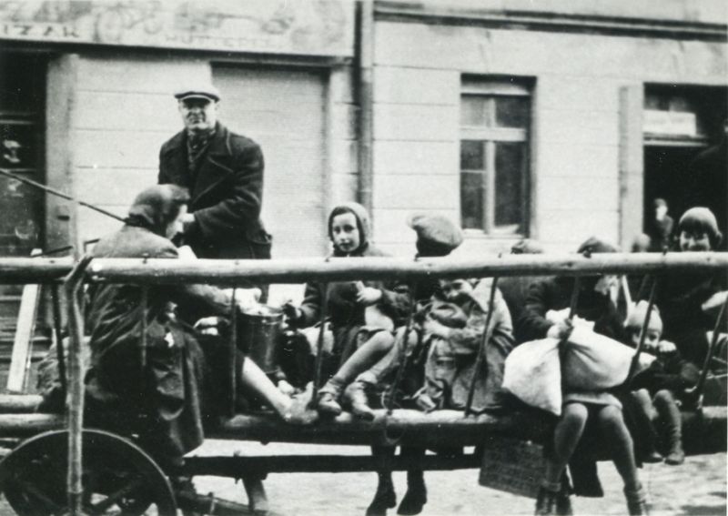 Displacements from Oświęcim. Children and a woman riding on a ladder cart. Horse-drawn cart driven by a driver.