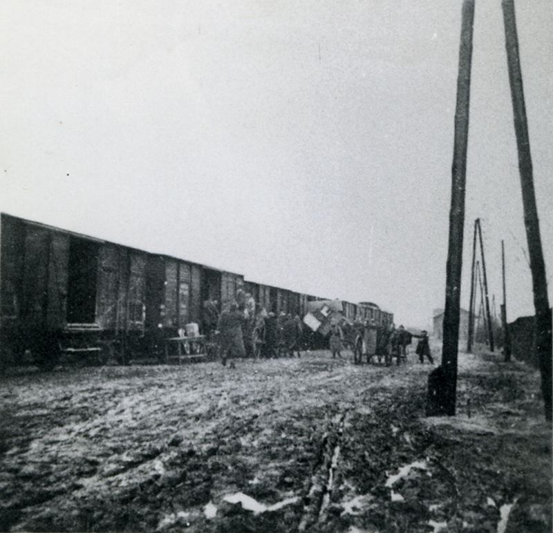 Loading furniture into freight wagons. The train is standing on a railway siding.