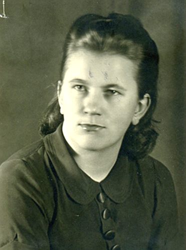 Young woman wearing a blouse with collar, serious expression, looks to the side, posed photo.