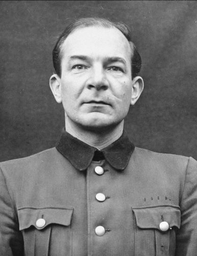 Portrait of a middle-aged man in uniform. Hair combed back. Looking straight ahead beyond the camera lens. Serious, focused face.