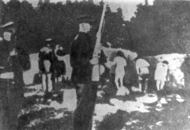 Nagie kobiety oczekujące na polanie w lesie na egzekucję. Na pierwszym planie pilnujący ich litewscy policjanci w mundurach, z karabinami.