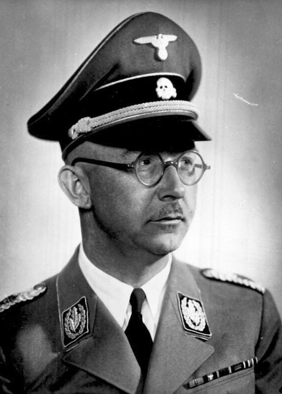 Portrait photograph of a man in German uniform. Face focused, facing to the side. Horn-rimmed glasses. On his head a cap - part of the uniform. On the cap a skull together with crossed tibias - Totenkopf.