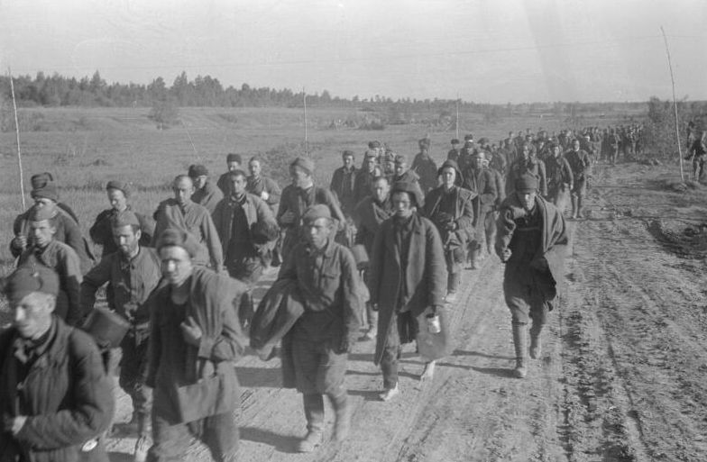 Soviet soldiers walking along a country road. They have incomplete uniforms, some are barefoot.