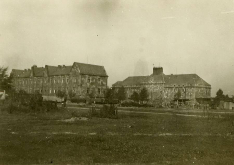 Two vast two-storey plastered buildings. Located opposite each other. Sloping roofs.