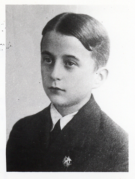 Portrait photograph of Mieczysław Popkiewicz in his teens. Face focused, serious, gaze directed to the side. Dressed in a jacket, a shirt and a tie. A scouting cross pinned into the lapel of his jacket.