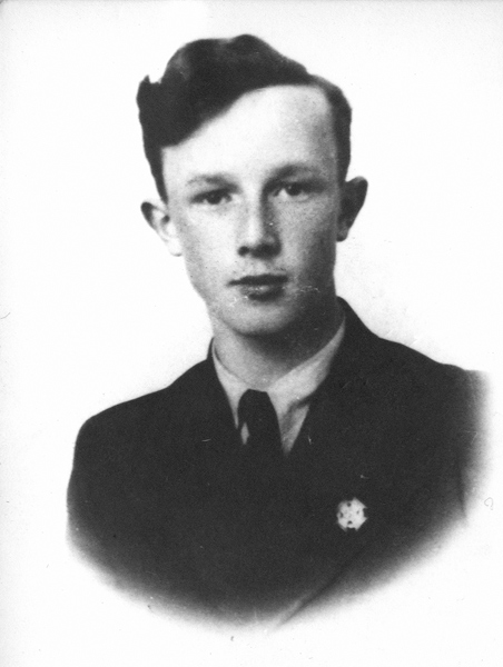 Portrait photograph of Mieczysław Albin in his teens. Face focused, serious, gaze directed straight ahead. Dressed in a jacket, a shirt and a tie. A scouting cross pinned into the lapel of his jacket.