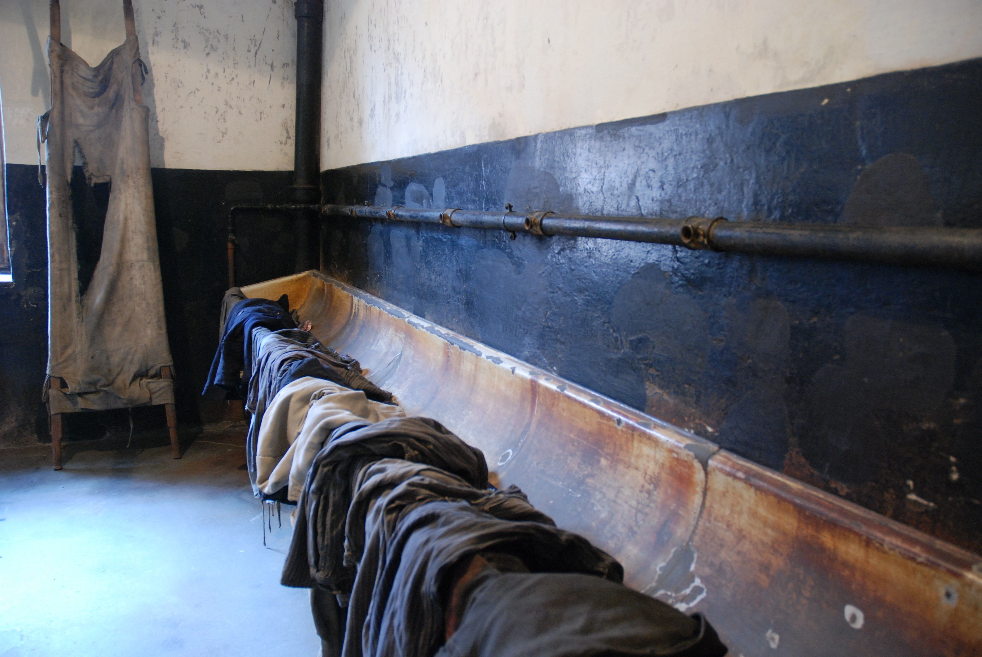Changing room in block 11. On the left, a stretcher leaning against the wall. On the right, an oblong washbasin - with clothes hanging over it.