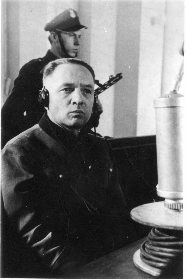 Portrait photograph of Rudolf Höss with headphones on, taken during his trial before the Supreme National Tribunal in Warsaw. Serious expression on his face, gaze directed to the side.