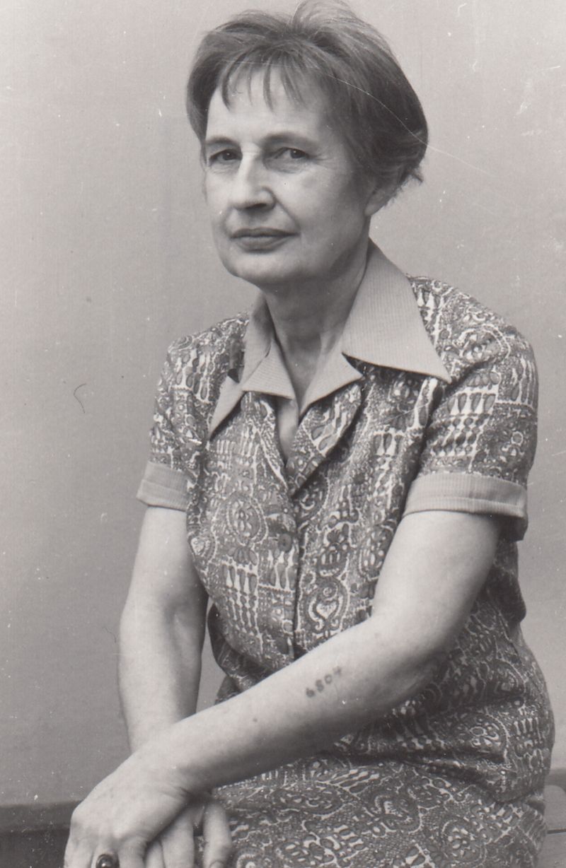 A photographic portrait of Janina Tollik with a tattoo on her arm.