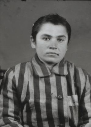 A woman on the left dressed in a striped prisoner uniform with a camp number on her left side.