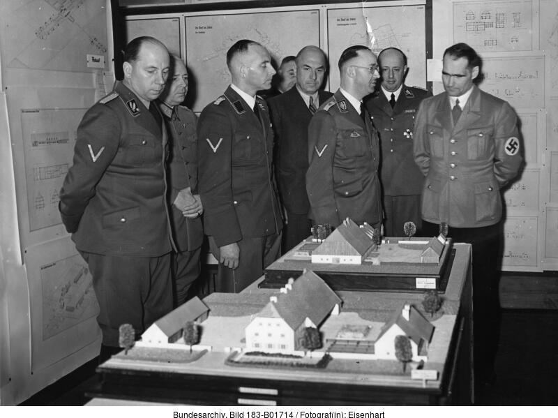 Men in uniform stand around a mock-up of buildings.