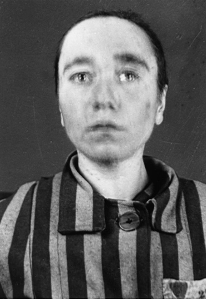 A woman on the left dressed in a striped prisoner uniform with a camp number on her left side.